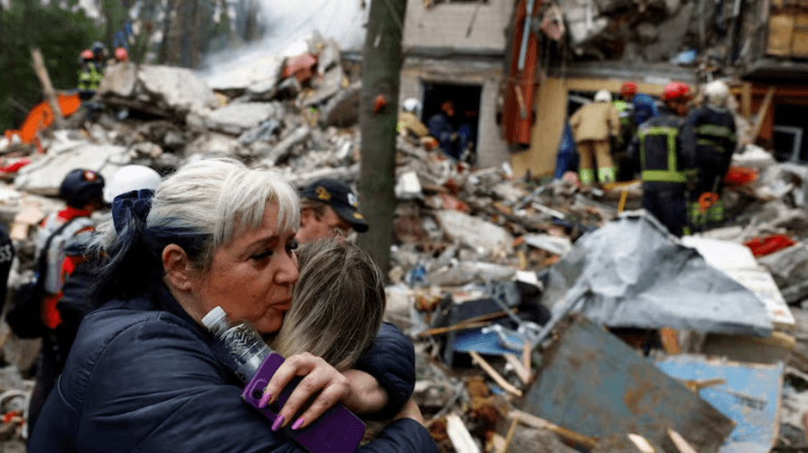 A woman embraces another woman as she waits for her son to be rescued from under the debris, at the site of an apartment building hit during Russian missile and drone strikes Thursday in Kyiv, Ukraine.