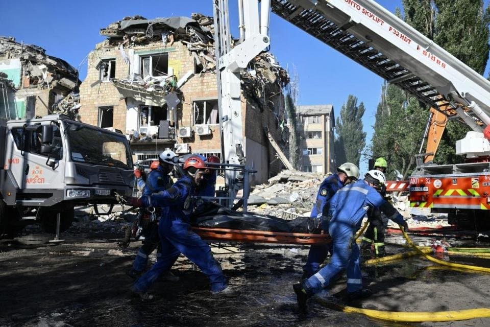 Ukrainian rescuers carry the body of a victim recovered from the site of a residential building, heavily damaged following a Russian missile strike in Kyiv.