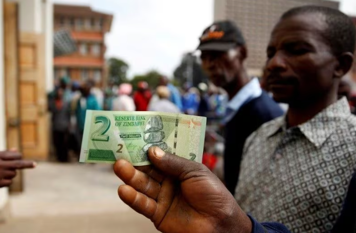A man poses with Zimbabwe's new two dollar banknote as customers queue outside a bank in Harare Zimbabwe November 12 2019 REUTERSPhilimon BulawayoFile Photo Acquire Licensing Rights | Report Focus News